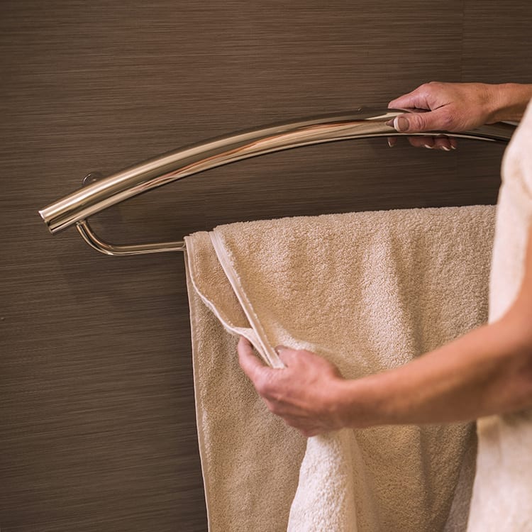 Invisia Towel Bar, with a towel hanging and a person holding the rail